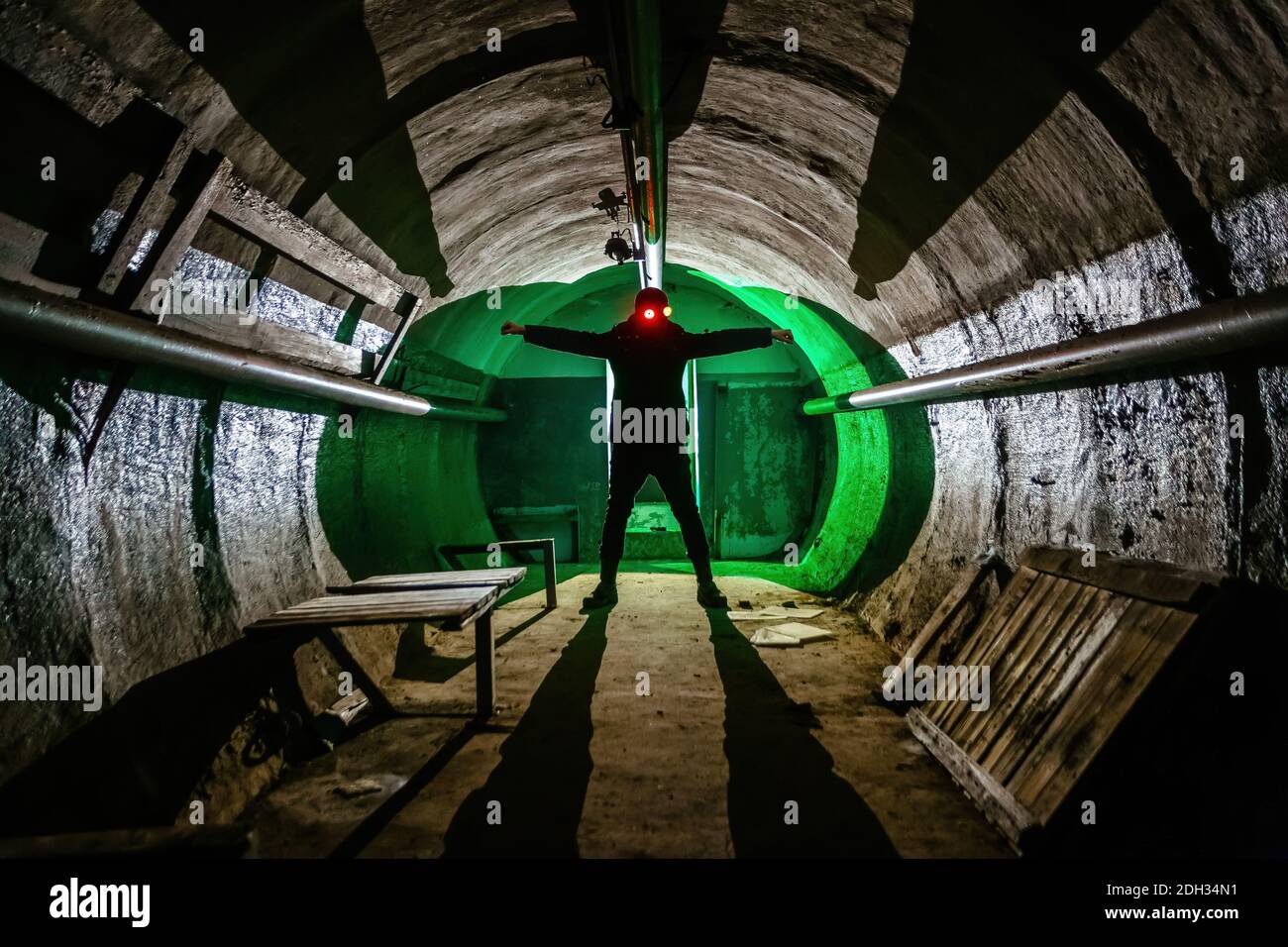 Creepy silhouette of man in mask with shining eyes in dark abandoned