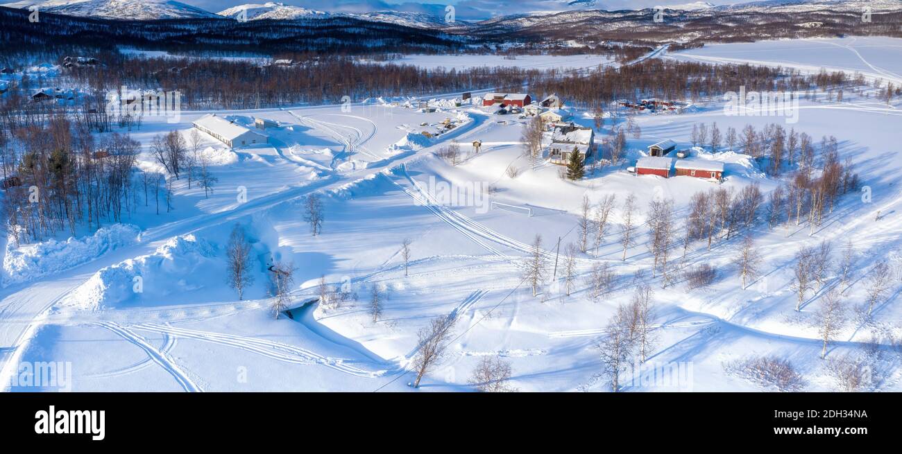 Scenic aerial view on small Tarna Vilt village in Swedish Lapland in winter cover, frosty sunny day. Roads, houses, frozen lakes, birch trees with Sca Stock Photo