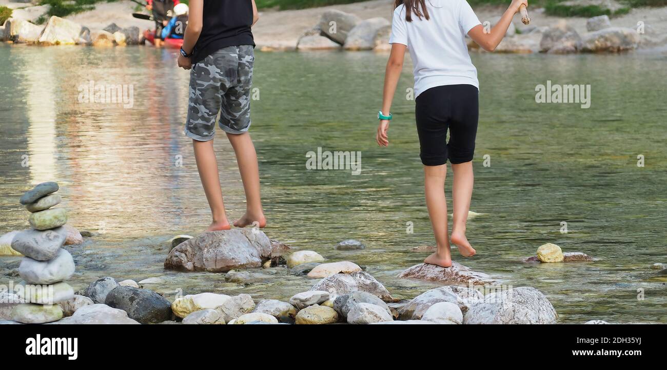 A couple of people walking on the rocks by the river and a tower of ...