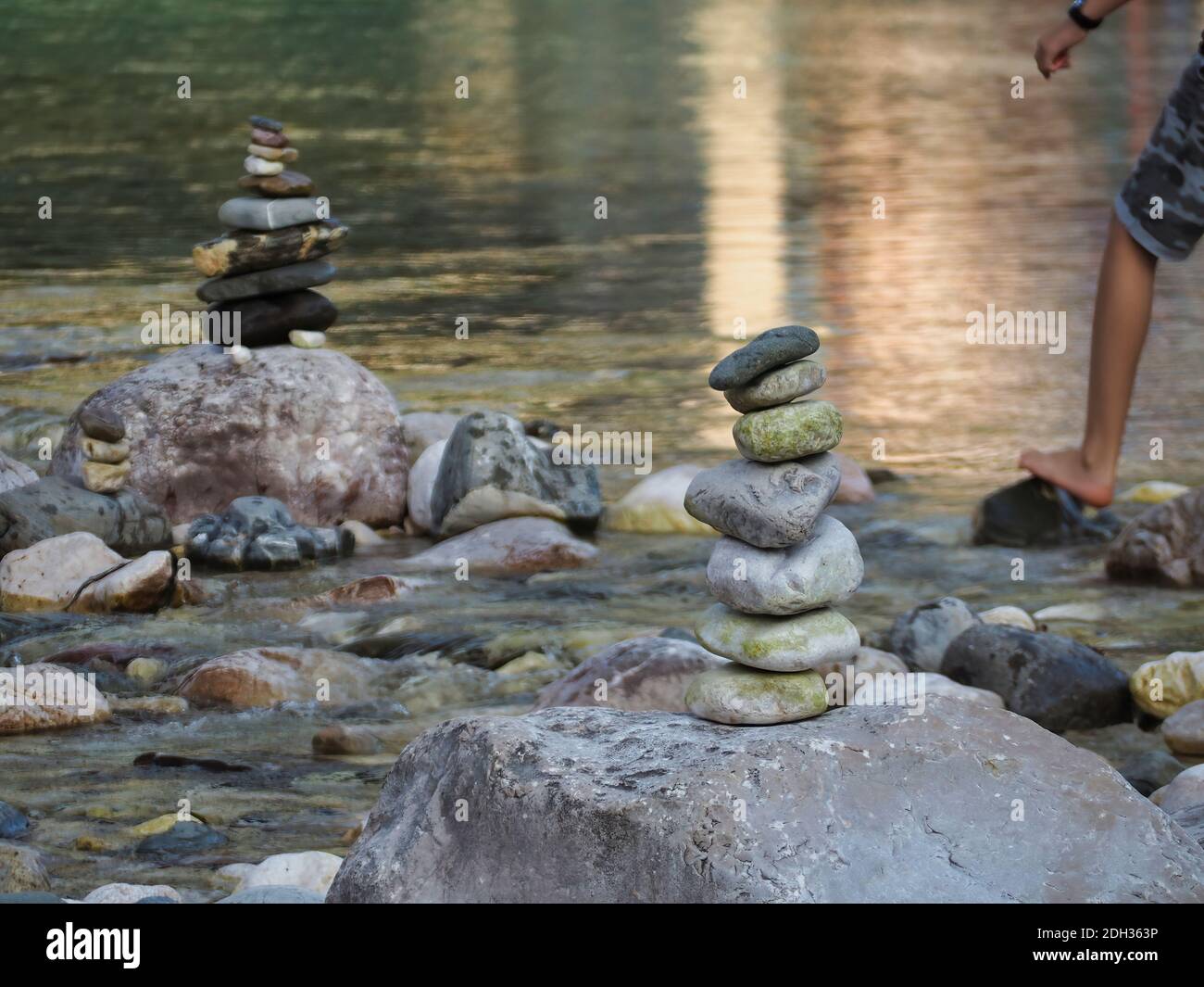 A person walking on the rocks by the river and a tower of rocks Stock ...