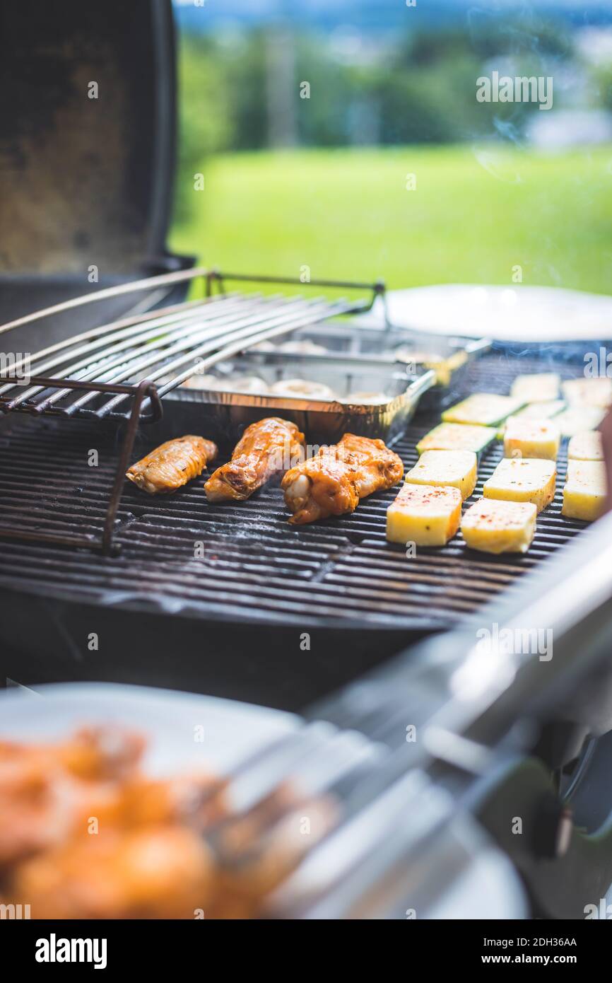 BBQ on weekend. Chicken wings, cheese and vegetables on gas grill. Outdoors Stock Photo Alamy