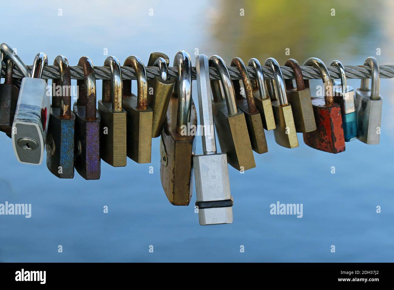 Old rusty metal padlocks hanging on string above river Stock Photo