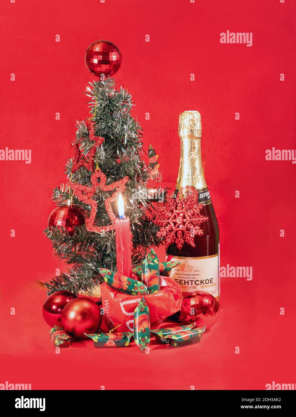 A small decorative spruce on the table, sweets popular in Russia, a burning candle and sparkling wine (by analogy with champagne according to Soviet t Stock Photo