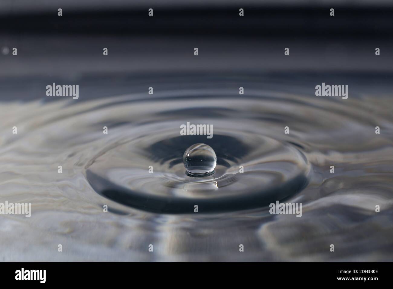 A closeup of a water droplet falling into the water Stock Photo - Alamy