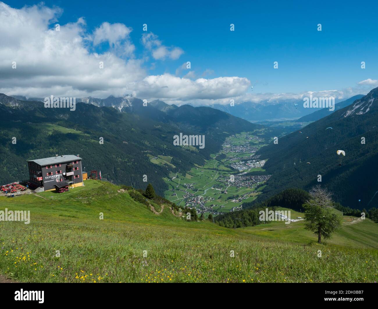 View over green Stubai valley and Neustift im Stubaital village with Elferhutte, grass meadow, moutain peaks and kites. Tirol Alps, Austria, Summer Stock Photo