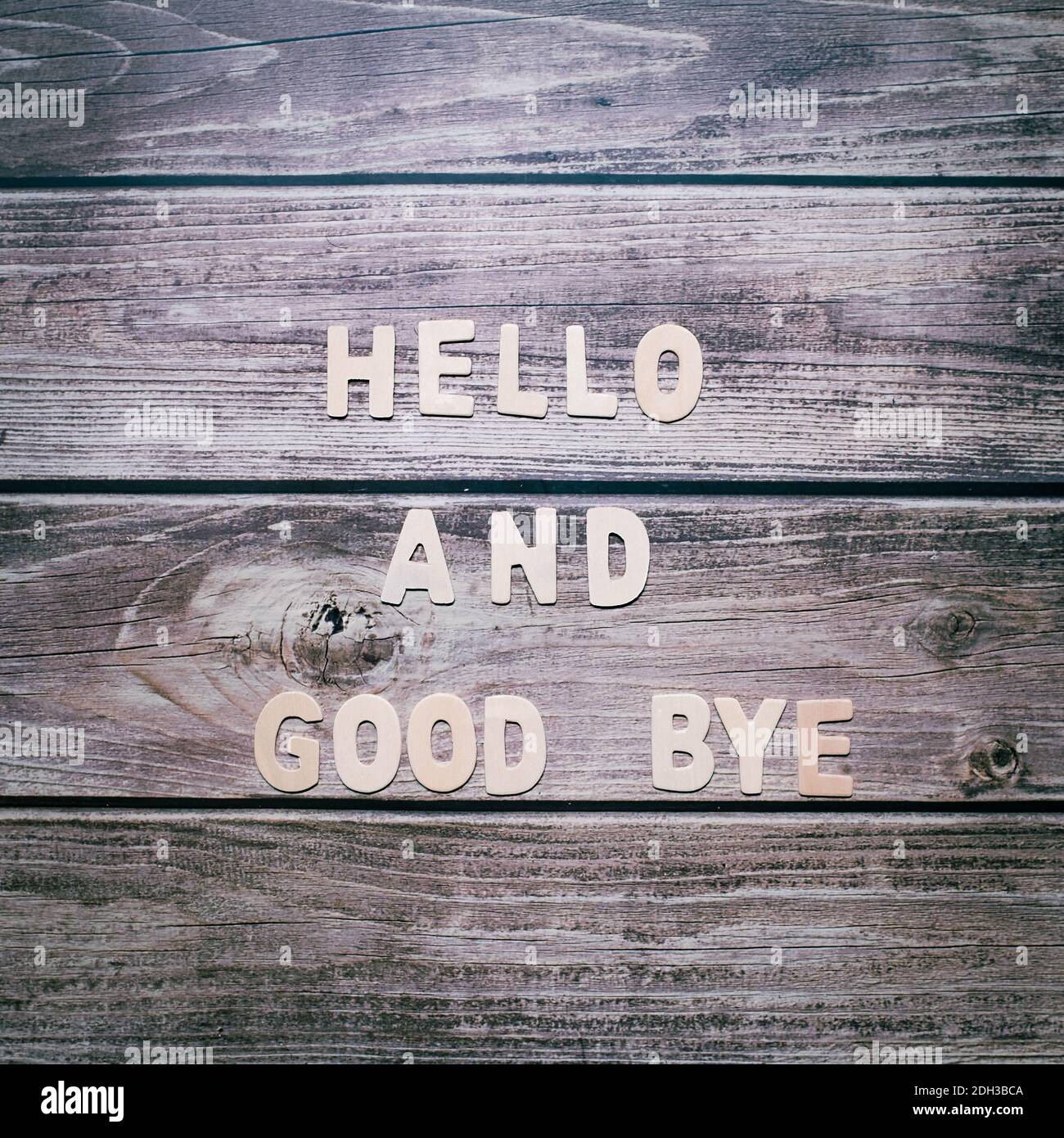Hello and good bye wooden letters written no a striped wooden background Stock Photo