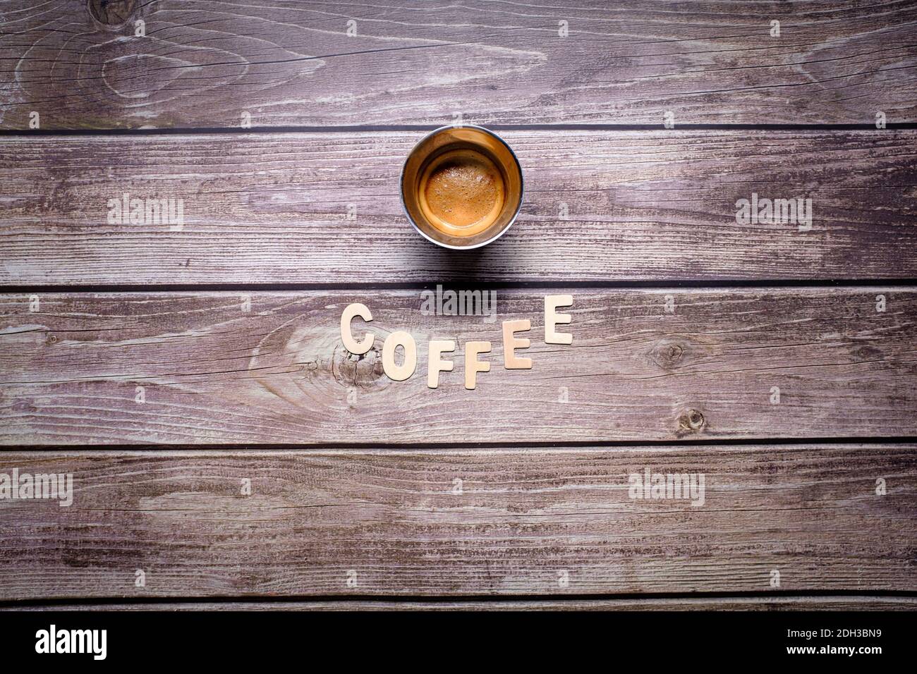 Brown espresso coffee with wooden letters spelling coffee on a wooden table Stock Photo