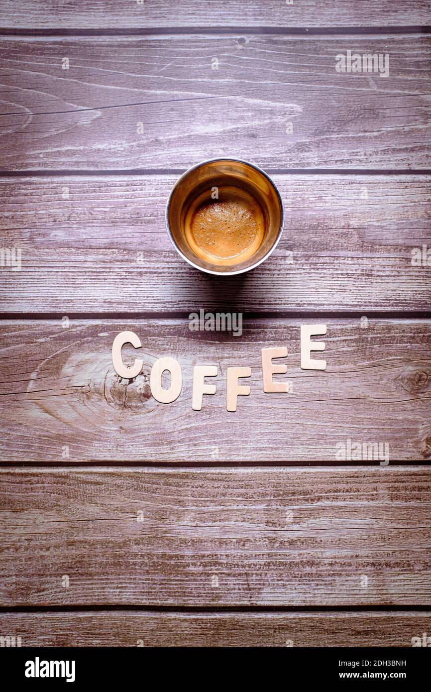 Brown espresso coffee with wooden letters spelling coffee on a wooden table Stock Photo