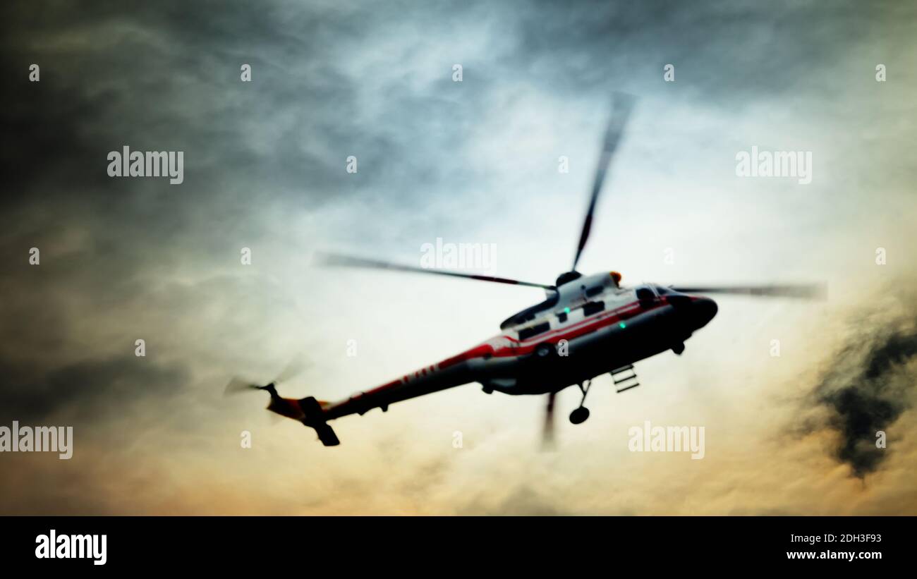 Blurred unrecognizable helicopter in a cloudy sky. Stock Photo