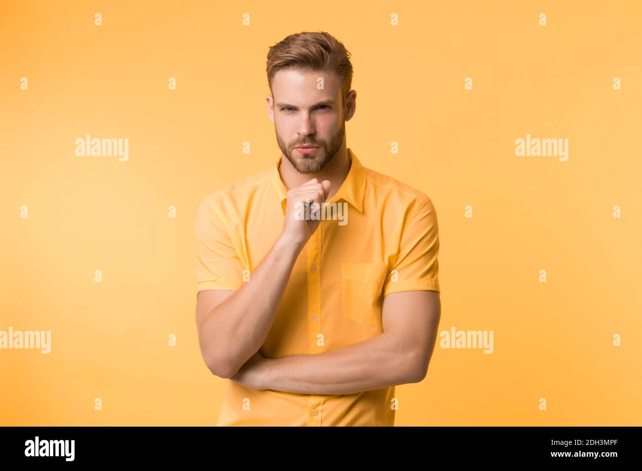 Asking himself. Handsome young man keeping hand on chin while stand ...