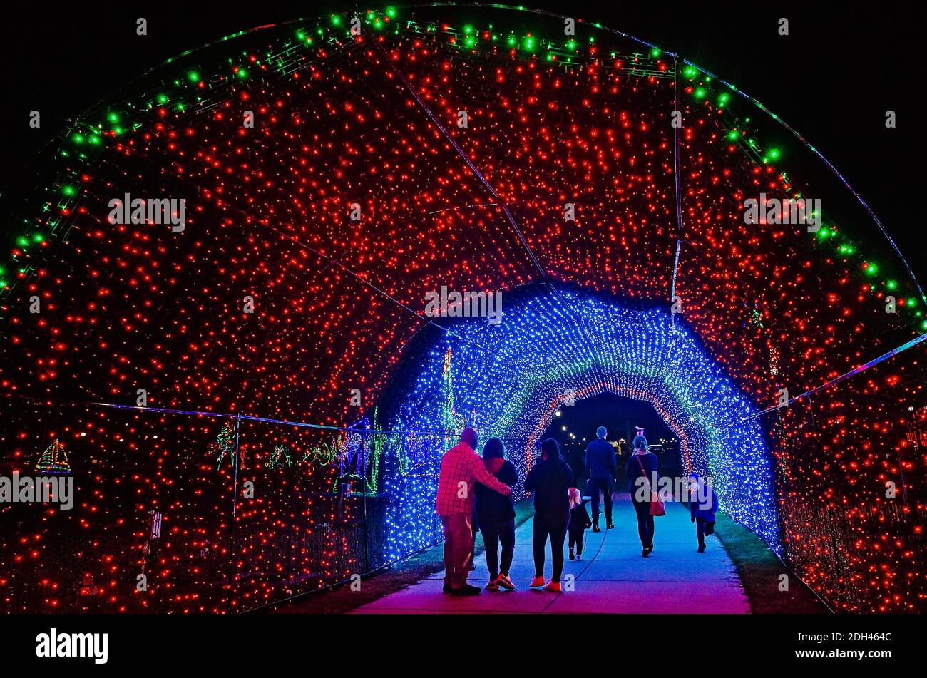 People walk through a LED Christmas lights tunnel during a holiday celebration in Jones Park, Dec. 5, 2020, in Gulfport, Mississippi. Stock Photo