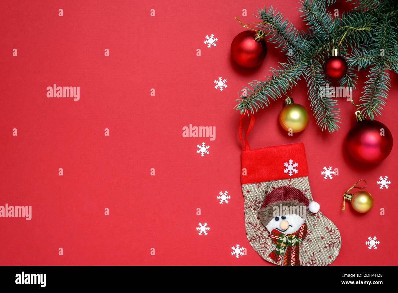 Christmas composition of fir tree branches, baubles, Christmas stocking and snowflakes on red background with copy space for text. Christmas and New Y Stock Photo