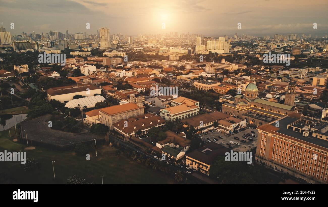 Sun shine over city roofs at green park aerial. Urban nature landscape at sunlight. Metropolis town cityscape with modern buildings at street. Philippines capital Manila Stock Photo