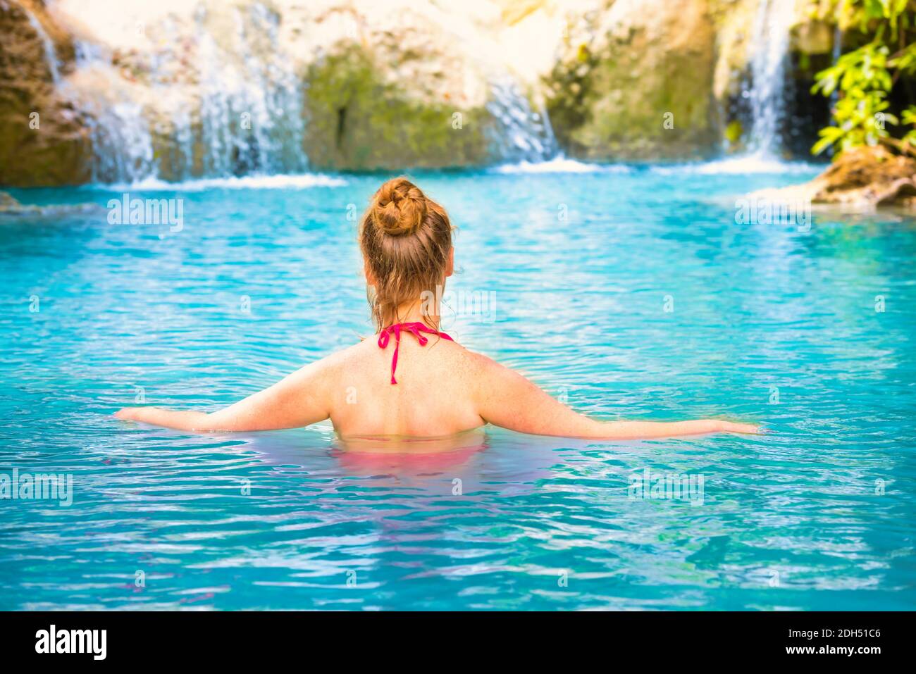 Rear view of young woman relaxes in emerald blue lake, Erawan National park, Thailand Stock Photo