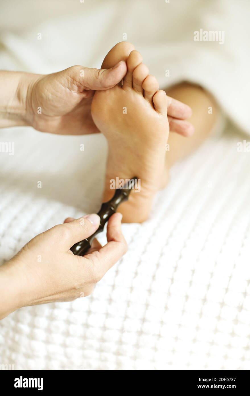 Crop masseuse making feet massage to client Stock Photo