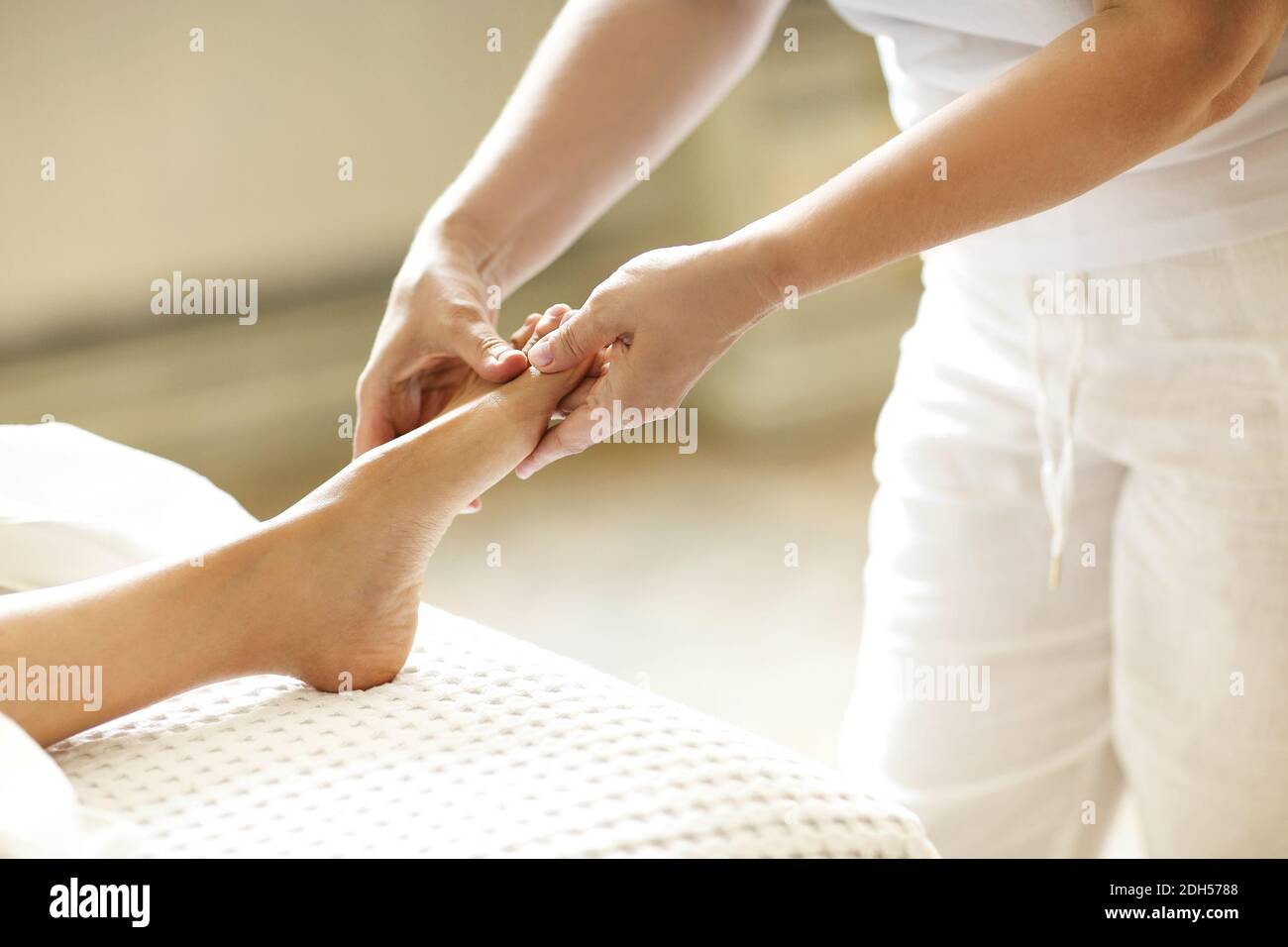 Crop masseuse making feet massage to client Stock Photo