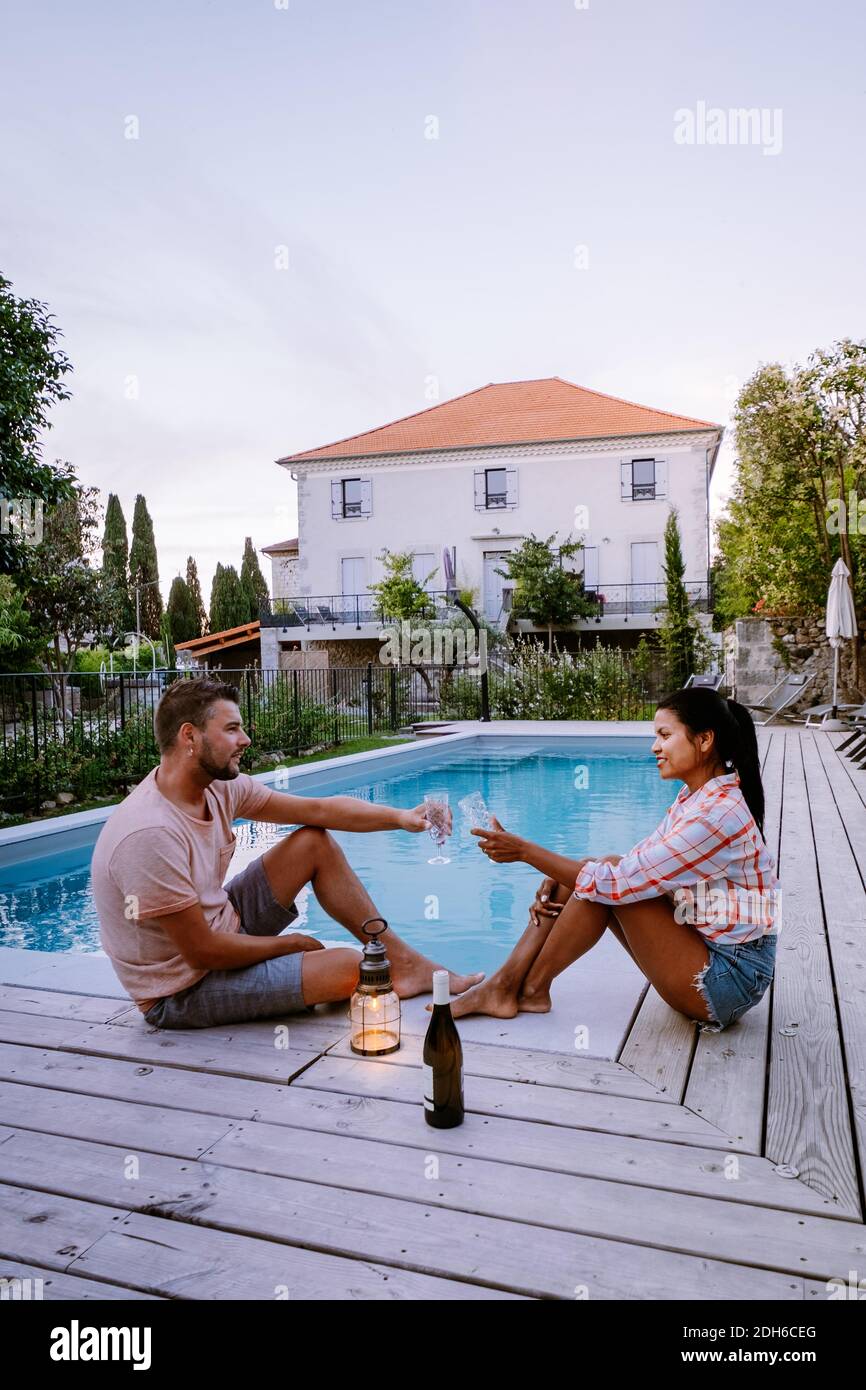 French vacation home with wooden deck and swimming pool in the Ardeche France. Couple relaxing by the pool with wooden deck duri Stock Photo