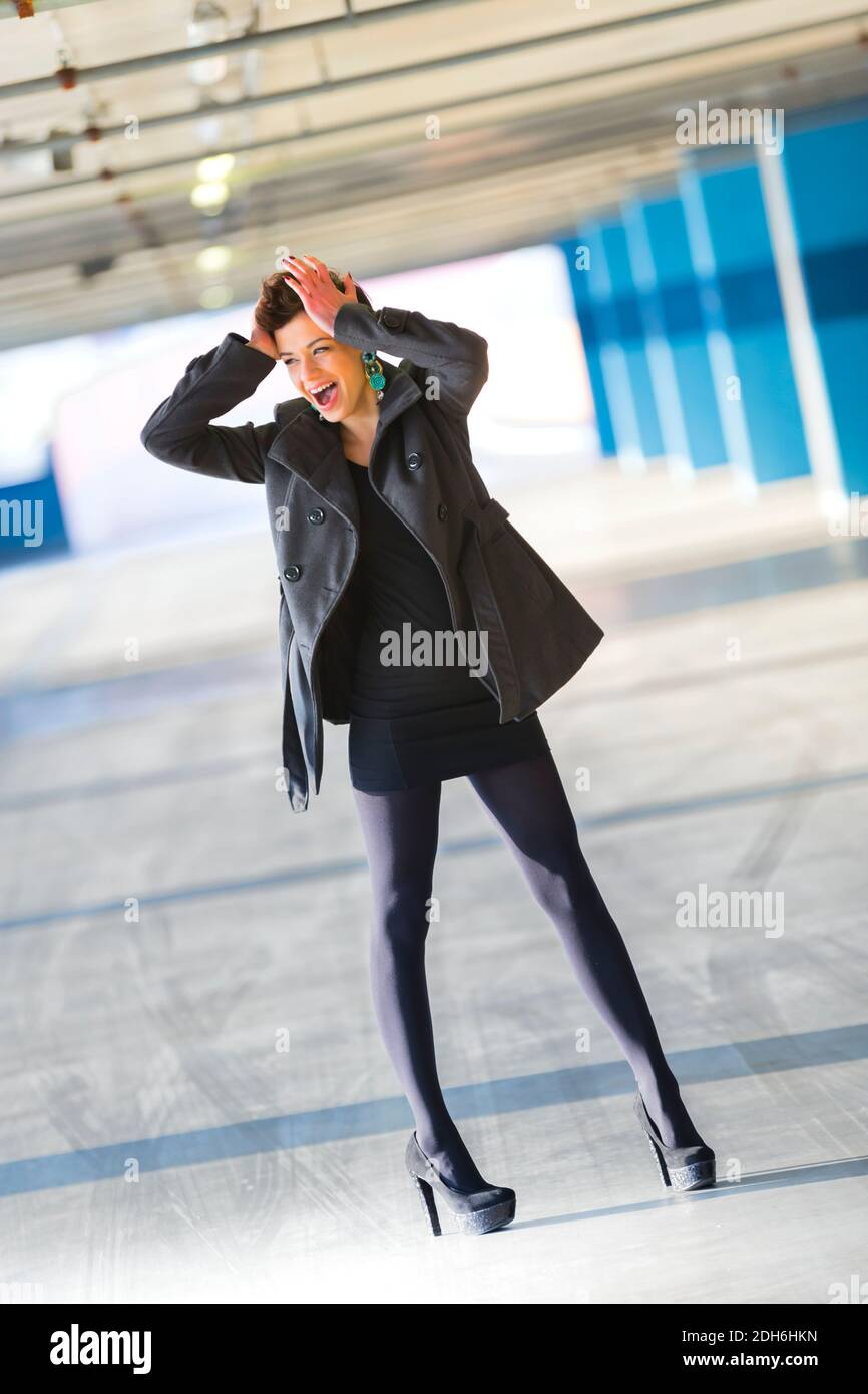 Teengirl legs heels Black outfit is panicking freaking out both hands are holding hold head hair shorthaired shorthair looking away aside legs heels Stock Photo