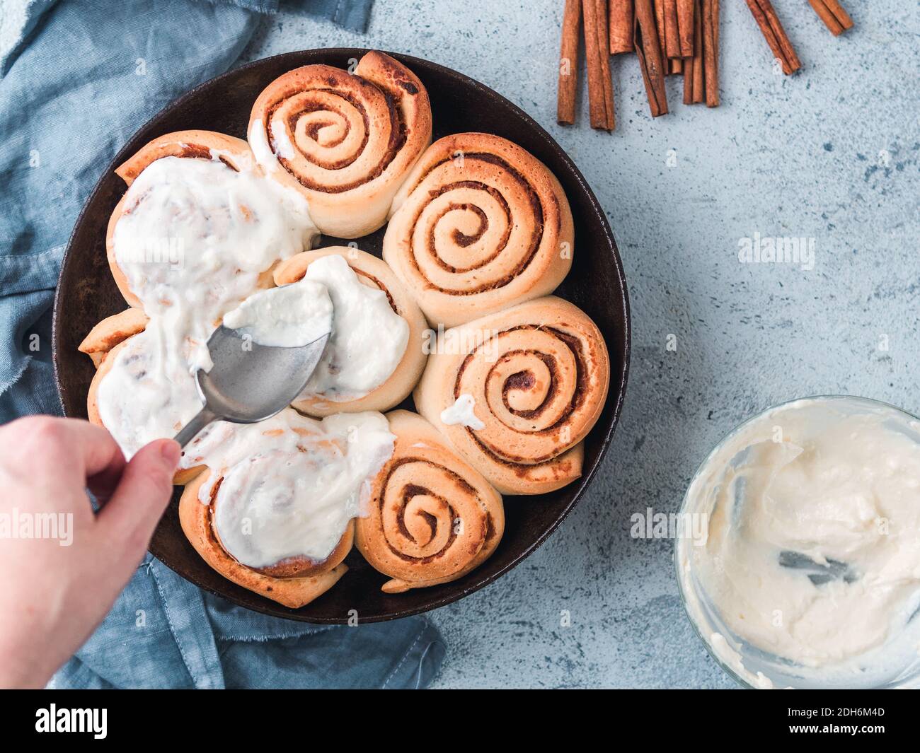 Hand Spreading Frosting on Cinnamon Rolls, copy space Stock Photo