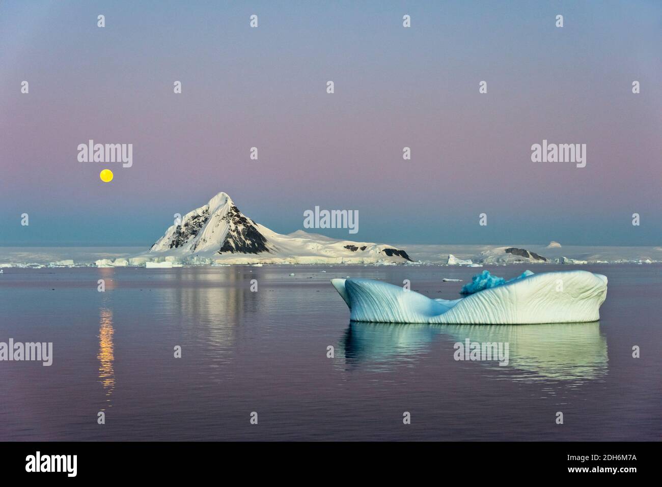 Moon over snow covered island and floating ice in South Atlantic Ocean, Antarctica Stock Photo