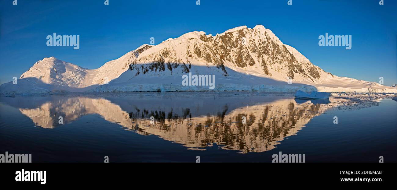 Snow covered island with reflection in South Atlantic Ocean, Antarctica Stock Photo