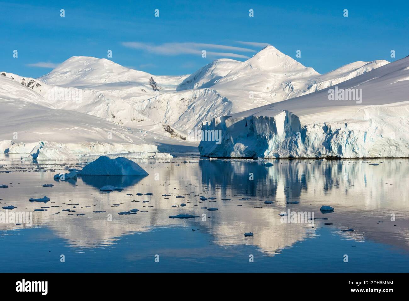 Snow covered island and iceberg with reflection in South Atlantic Ocean, Antarctica Stock Photo