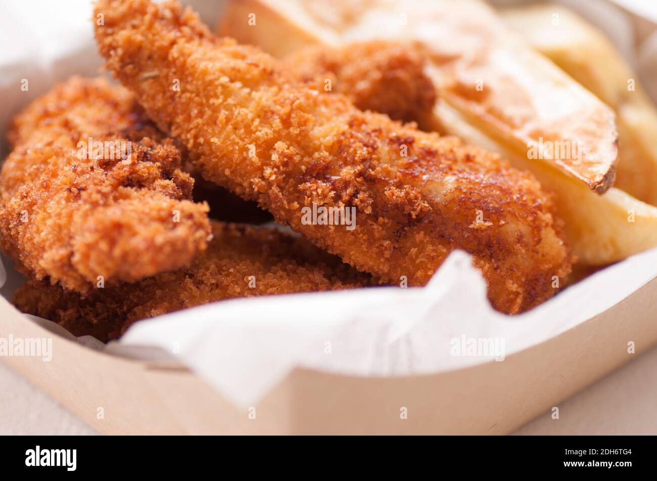 breaded chicken fingers and fries in a take out container Stock Photo