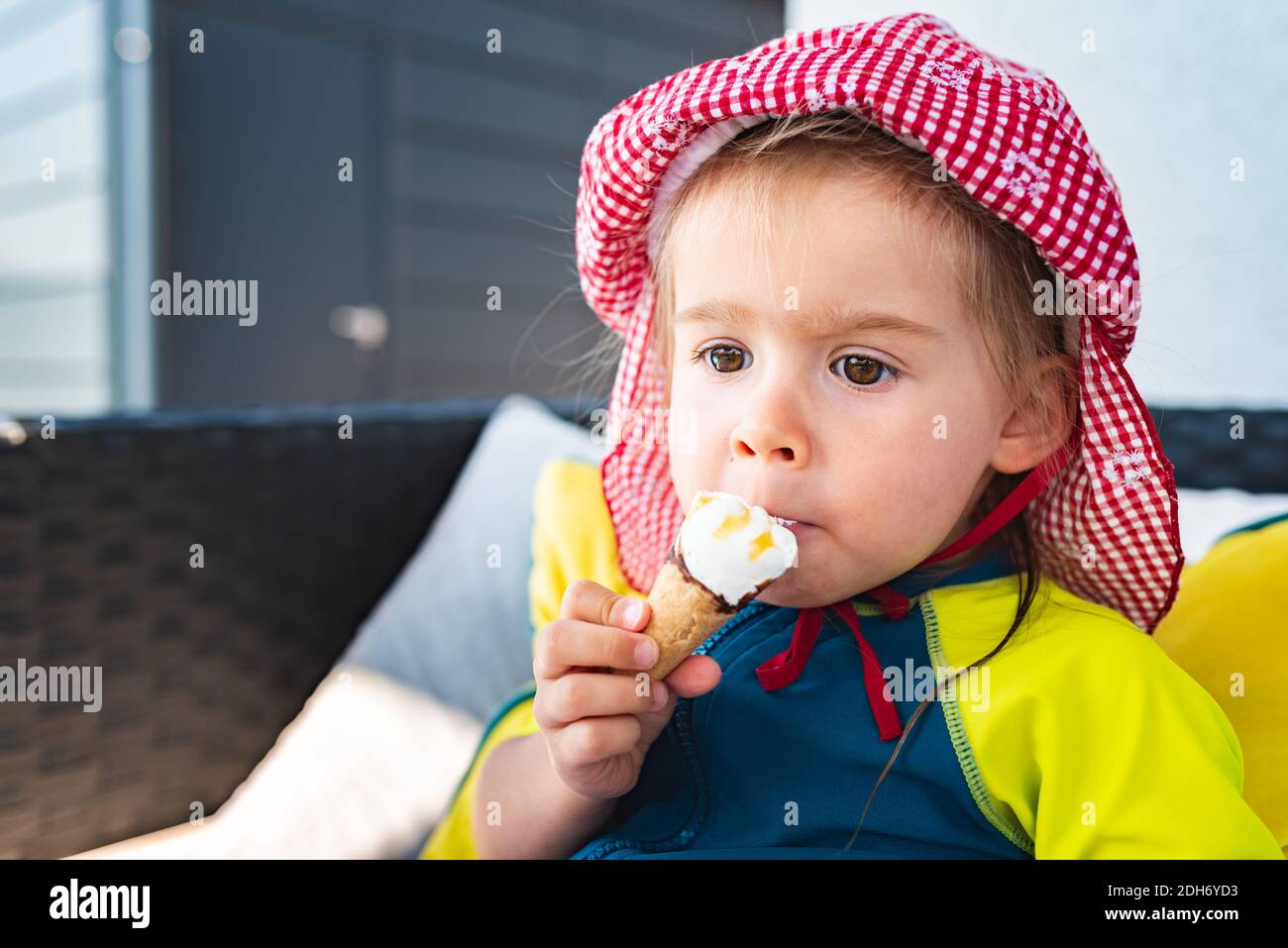 Portrait little child with big eyes licking icecream in summer. 2 year old baby girl. Stock Photo