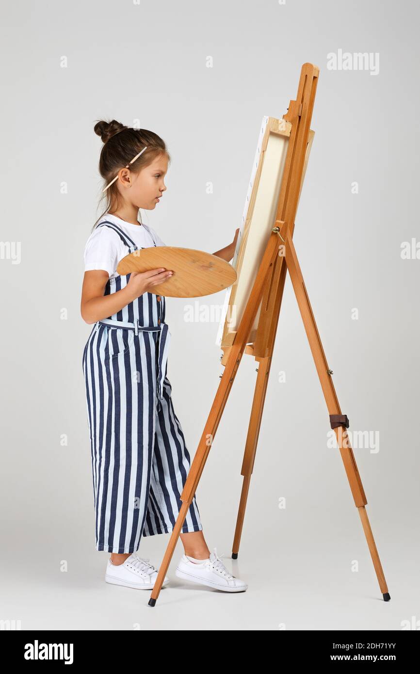 cute little girl holding a wooden art palette and brush on studio ...