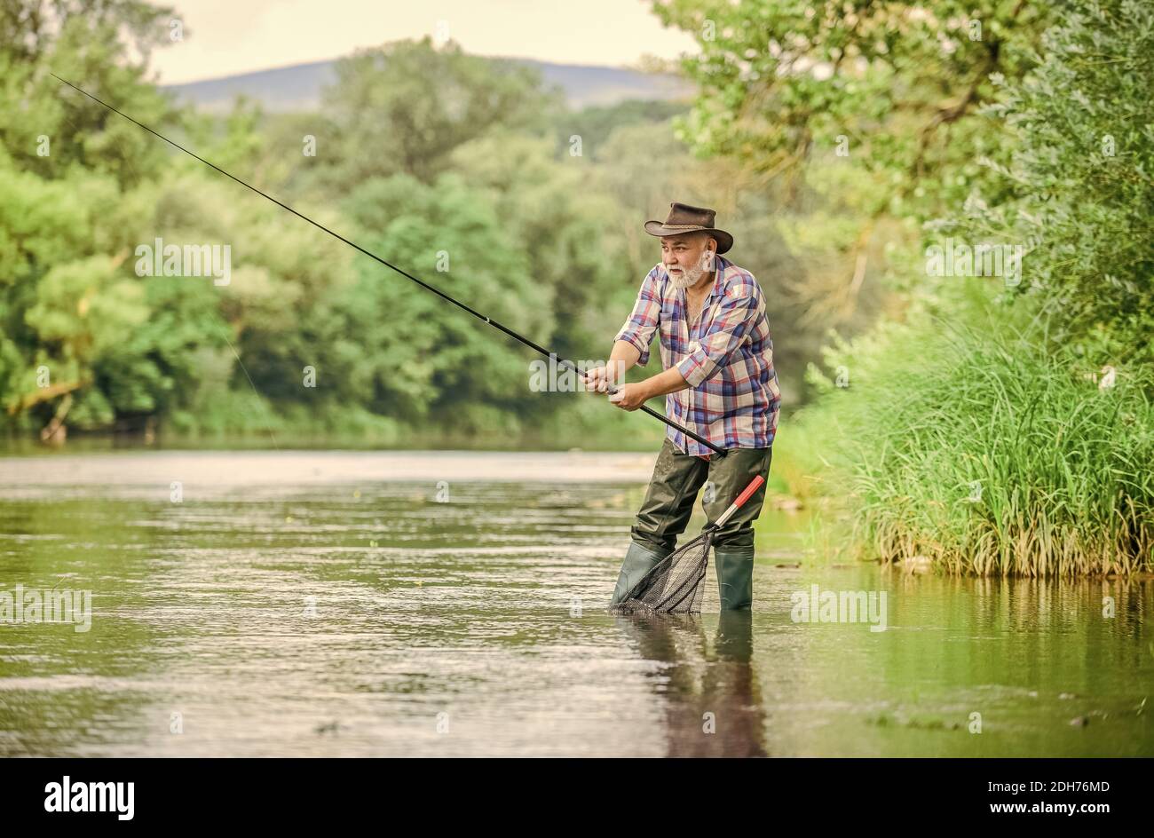 summer weekend. Big game fishing. man fly fishing. man catching fish. hobby  and sport activity. pothunter. retired bearded fisher. Trout bait. fisherman  with fishing rod. Men and fish are alike Stock Photo 