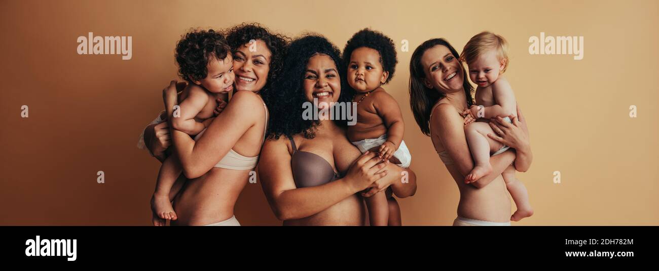 Proud mothers with postpartum bodies holding their babies. Three women with their children. Stock Photo