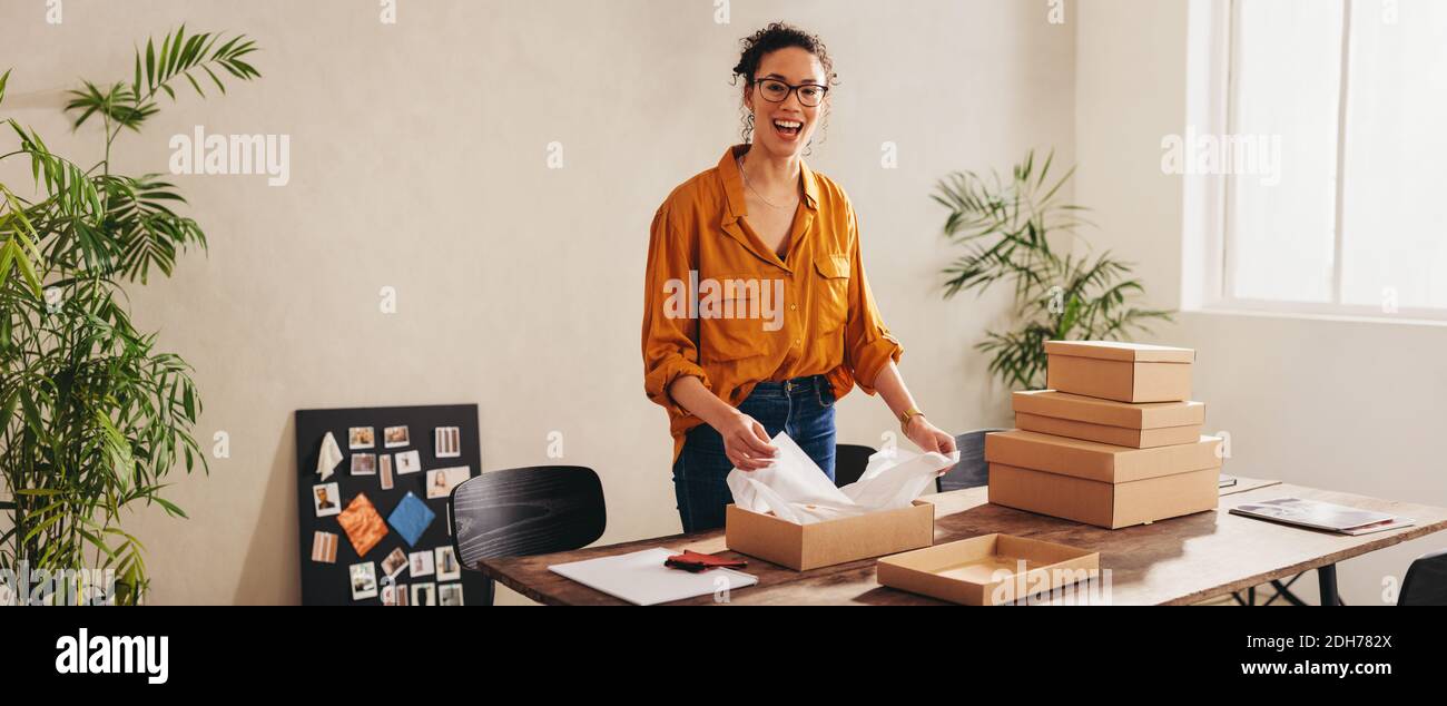 Small business owner packing a box for shipping to the online client. Female entrepreneur preparing the package to delivery. Stock Photo