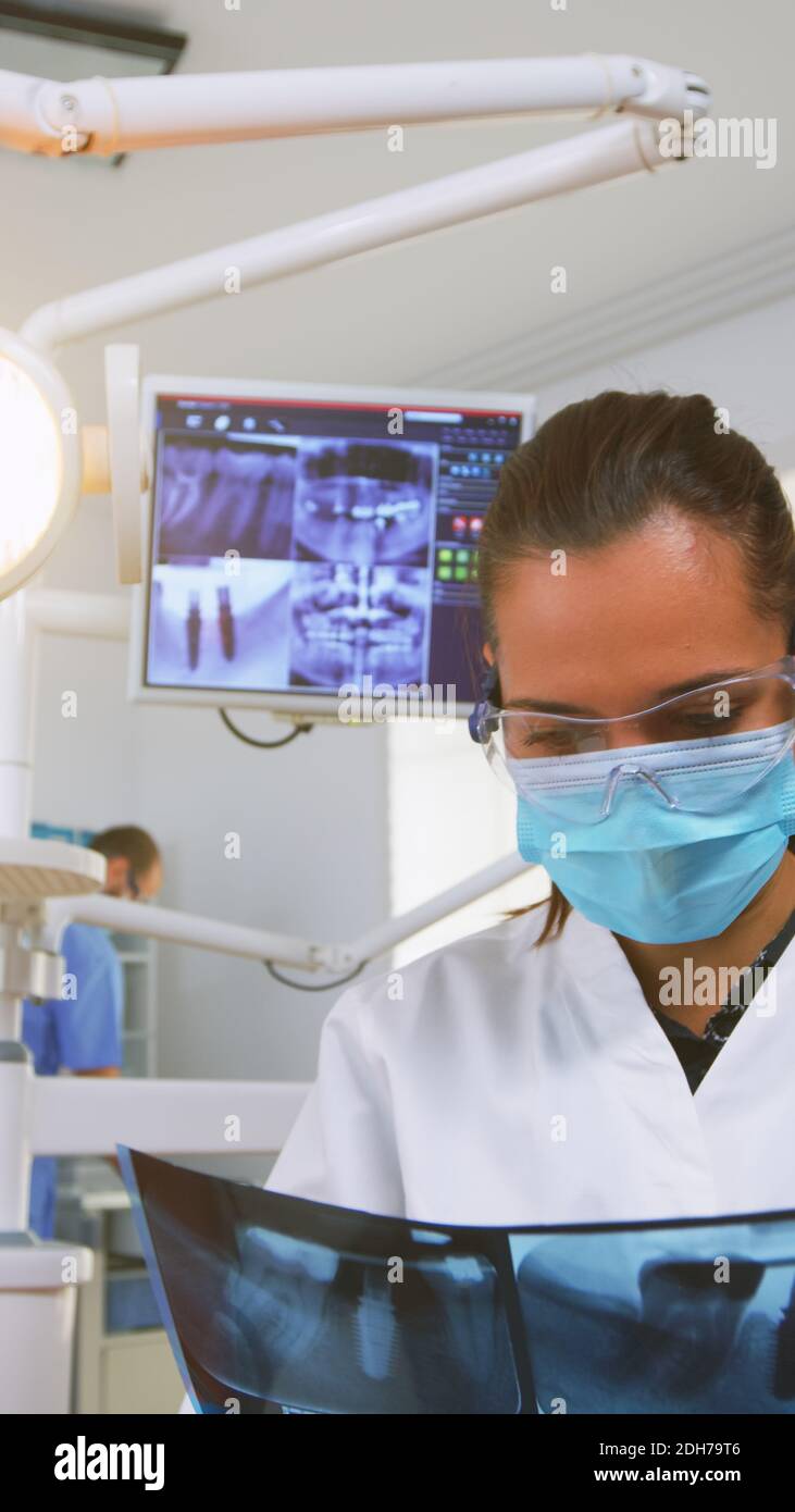 Dentist customizing light over the chair and analysing teeth xray