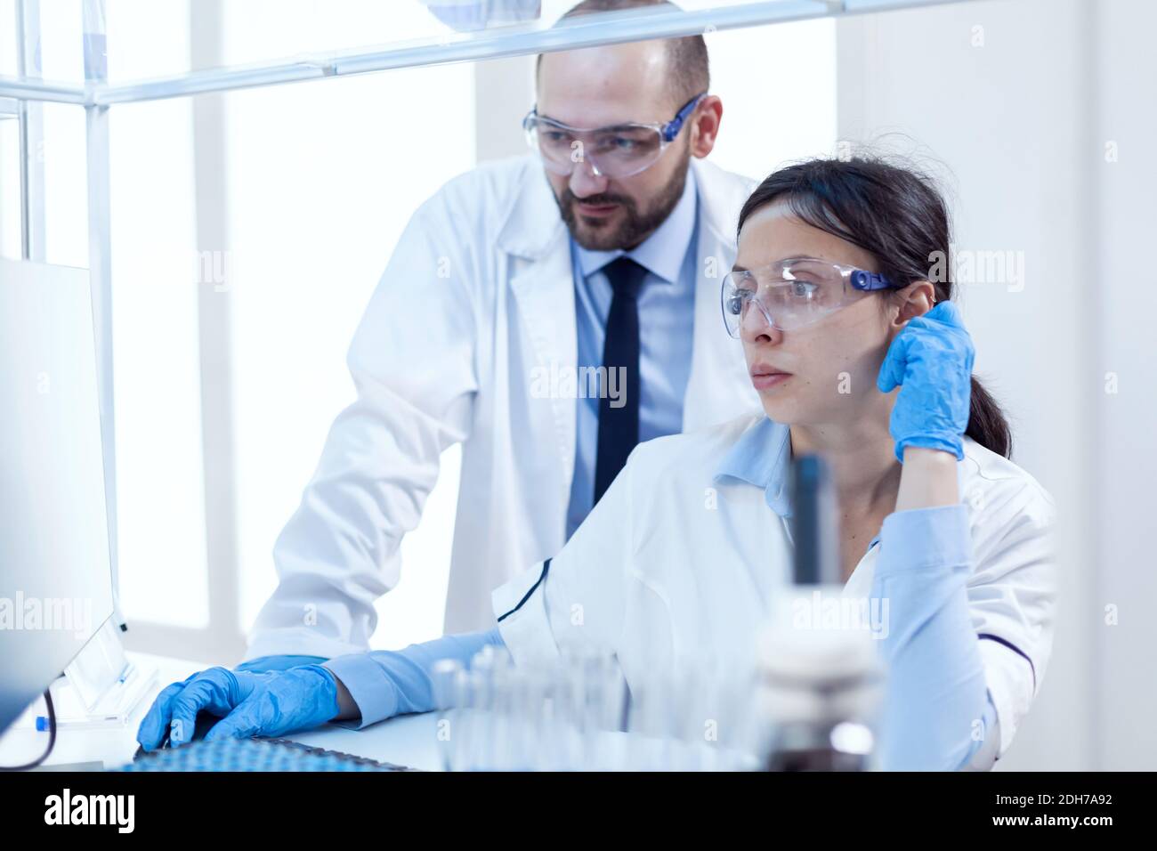 Male scientist helping assistant with study wearing protective