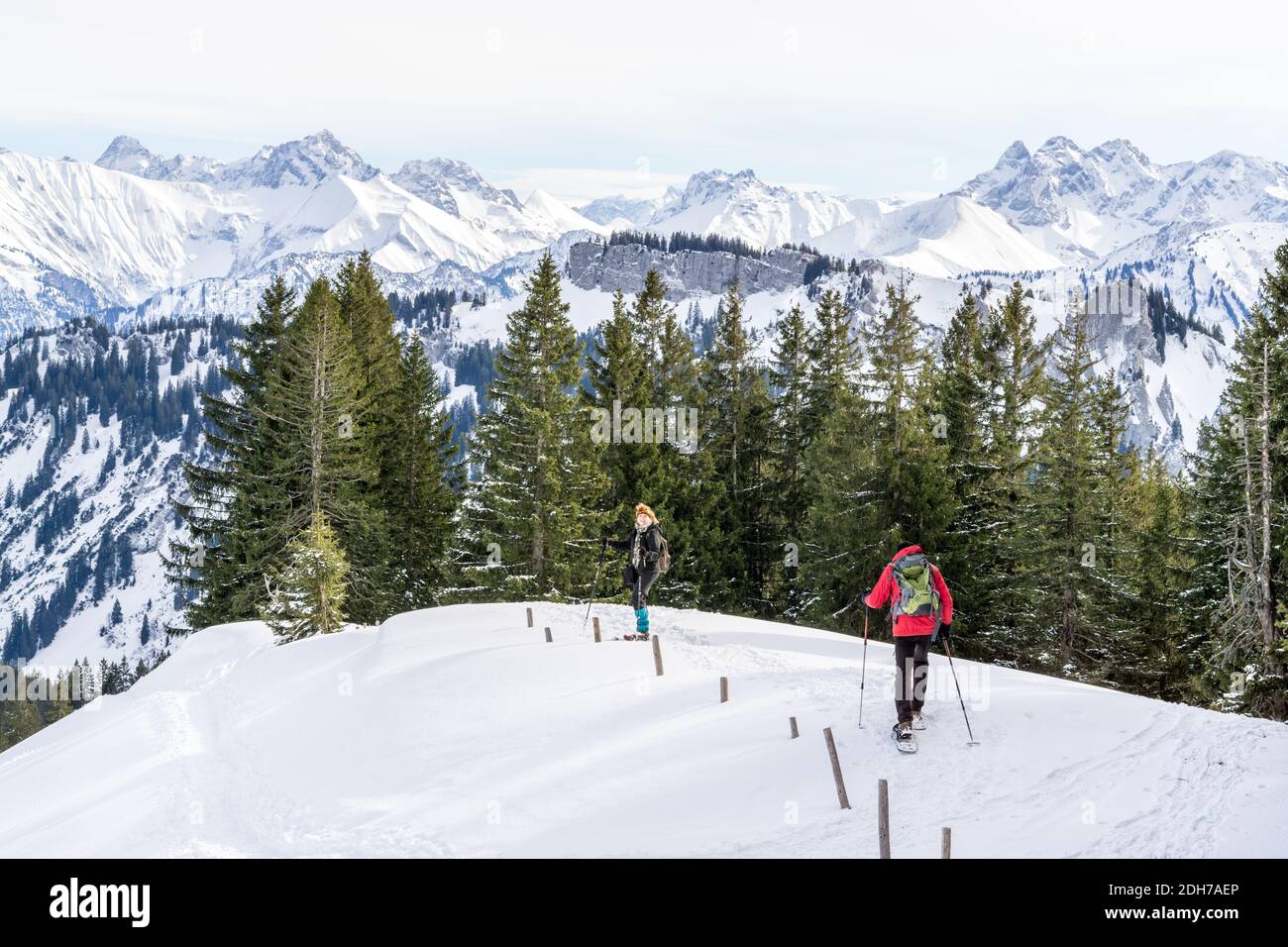 Senior couple is snowshoe hiking in alpine snow winter mountains. Allgau, Bavaria, Germany. Stock Photo
