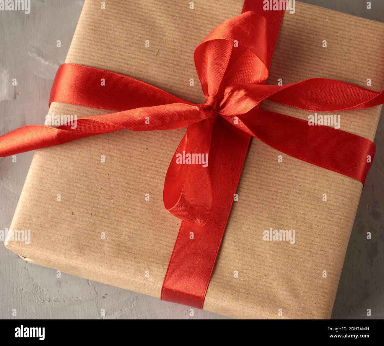 Knotted bow made of red silk ribbon on brown kraft paper background
