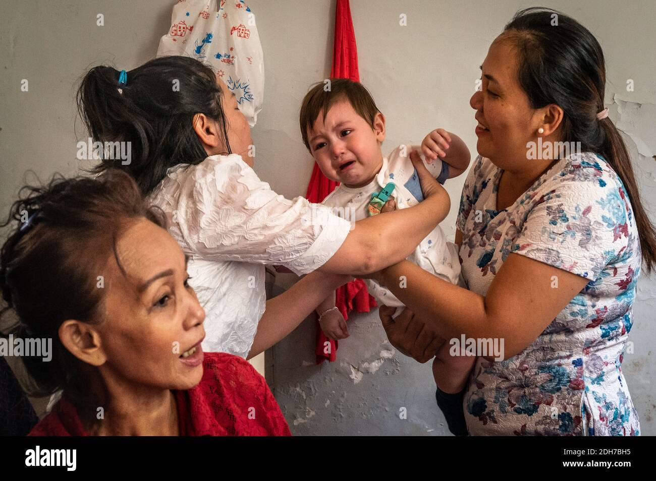 A crying Eurasian Vietnamese baby boy and his Vietnamese relatives, Ho Chi Minh City, Vietnam Stock Photo