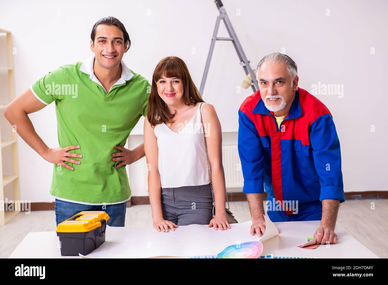 Young couple and old contractor in home renovation concept Stock Photo