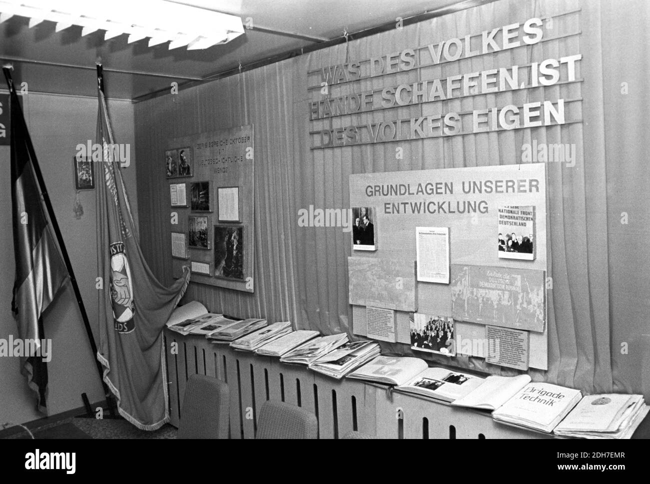 01 May 1982, Saxony, Eilenburg: 'The victorious October 1917 world historical turn' - A traditional cabinet in a VEB in May 1982. Behind the books and photo albums hang wall newspapers with the inscriptions 'What the people's hands create is the people's own' and 'Foundations of our development' with a picture with Otto Grotewohl and Wilhelm Pieck. Exact date of photograph not known. Photo: Volkmar Heinz/dpa-Zentralbild/ZB Stock Photo