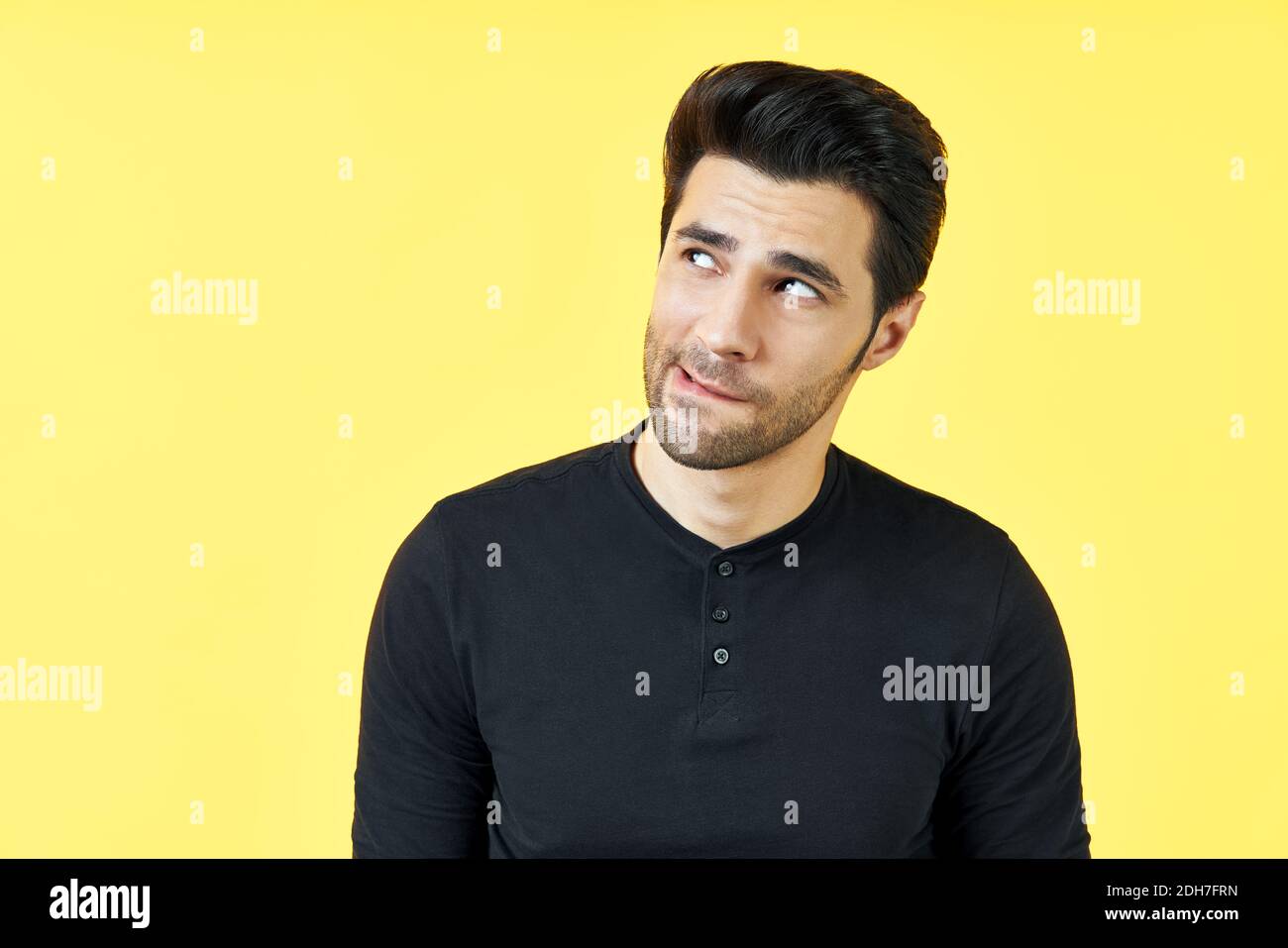 Confused thoughtful man have a doubt over yellow background. Stock Photo