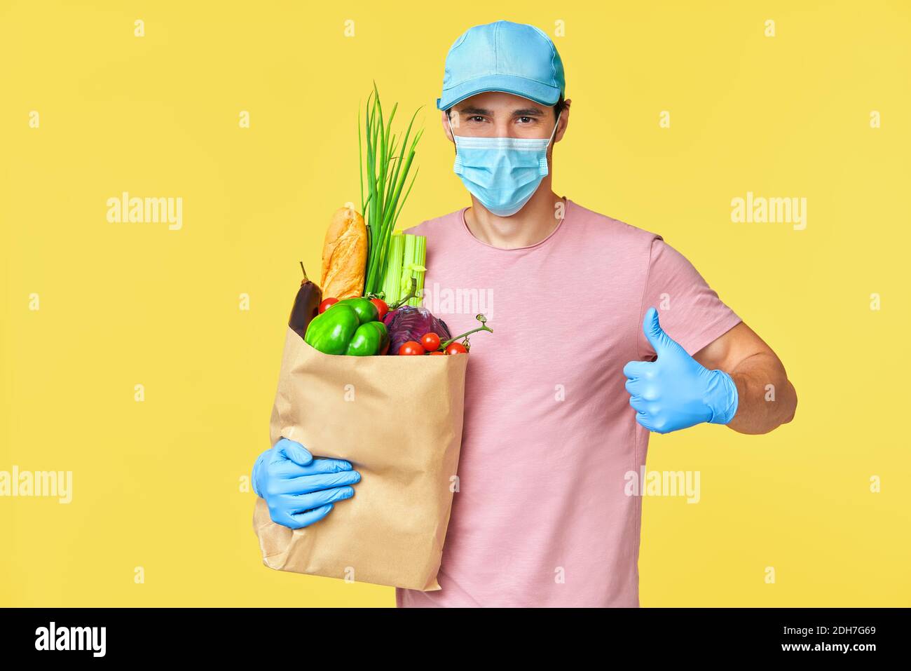 Delivery man giving food in paper bag wearing face mask and gloves as ...
