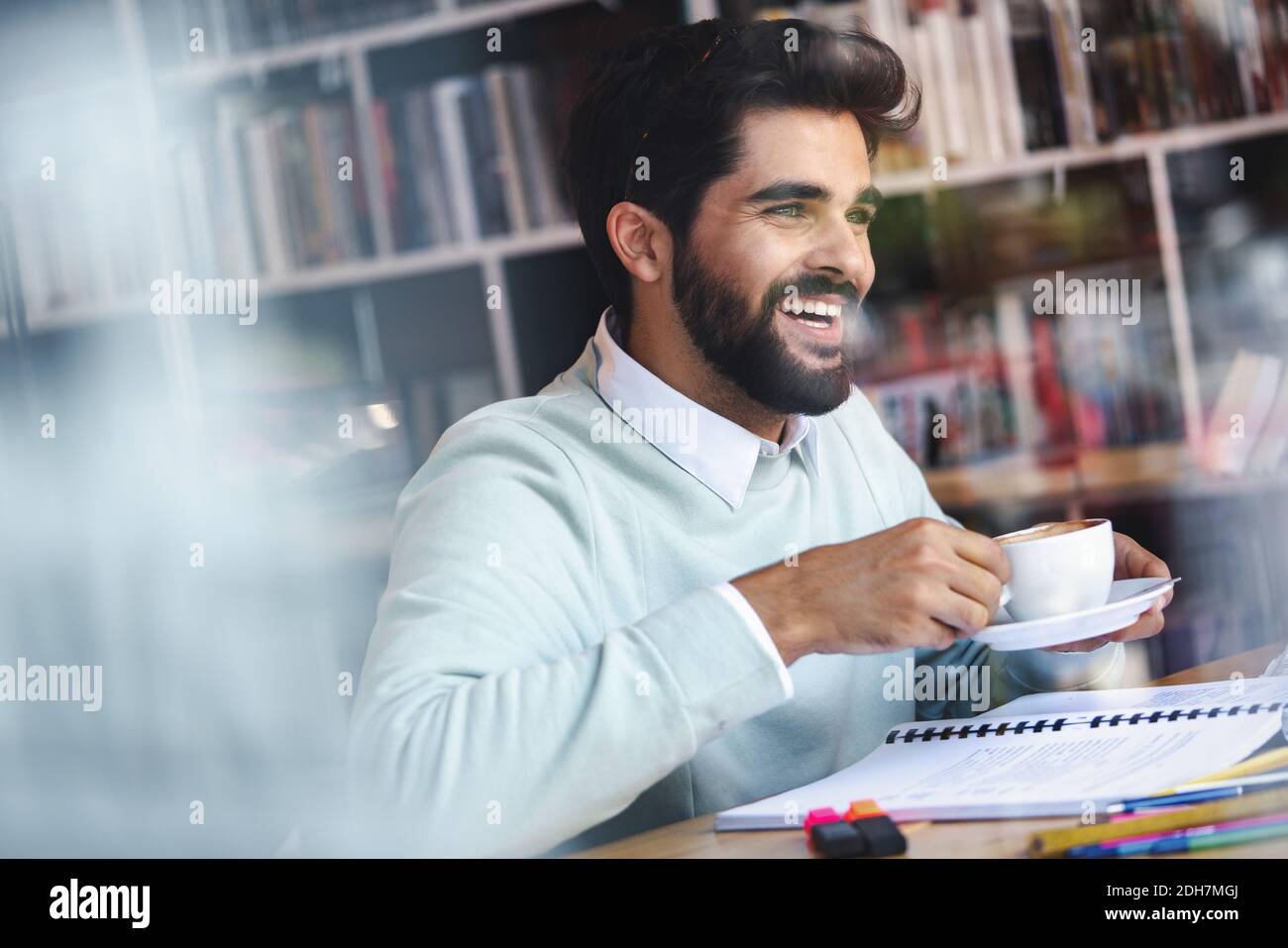 Portrait of young guy drinking coffee while studying in cafe Stock