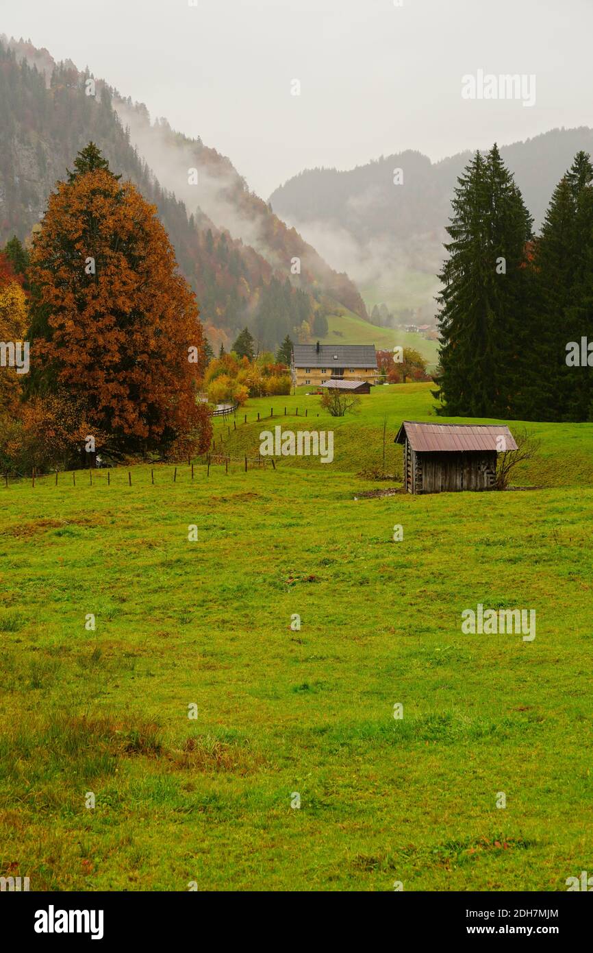 A vertical shot of a wooden hut in a meadow in the German Alps near Oberstdorf, Germany Stock Photo