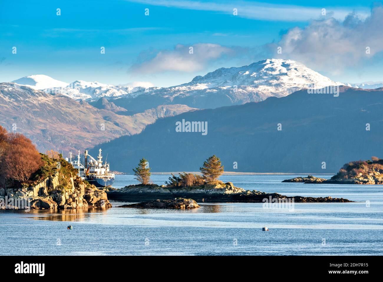 KYLE OF LOCHALSH  ROSS-SHIRE SCOTLAND RUGGED COASTLINE BOATS MOORED ALONG THE SHORE OF LOCH ALSH SNOW ON THE HILLS Stock Photo