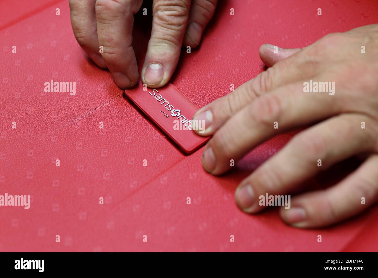 Closeup of workers hands putting label on suitcase at a Samsonite production line in Oudenaarde, Belgium. Stock Photo