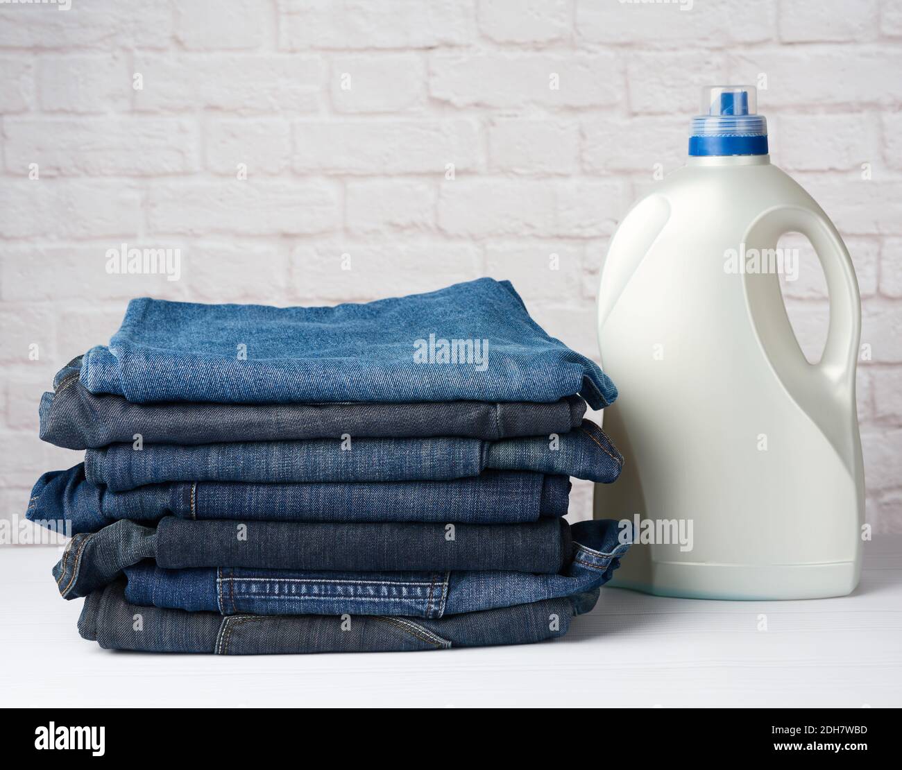 Stack of folded blue jeans and plastic bottle with washing gel Stock