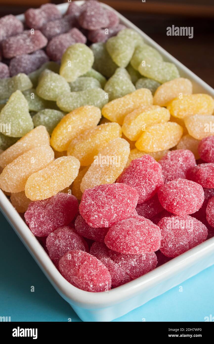 Close-up of red sugar sweeties with colorful candies out of focus background. High in sugar foods. Stock Photo