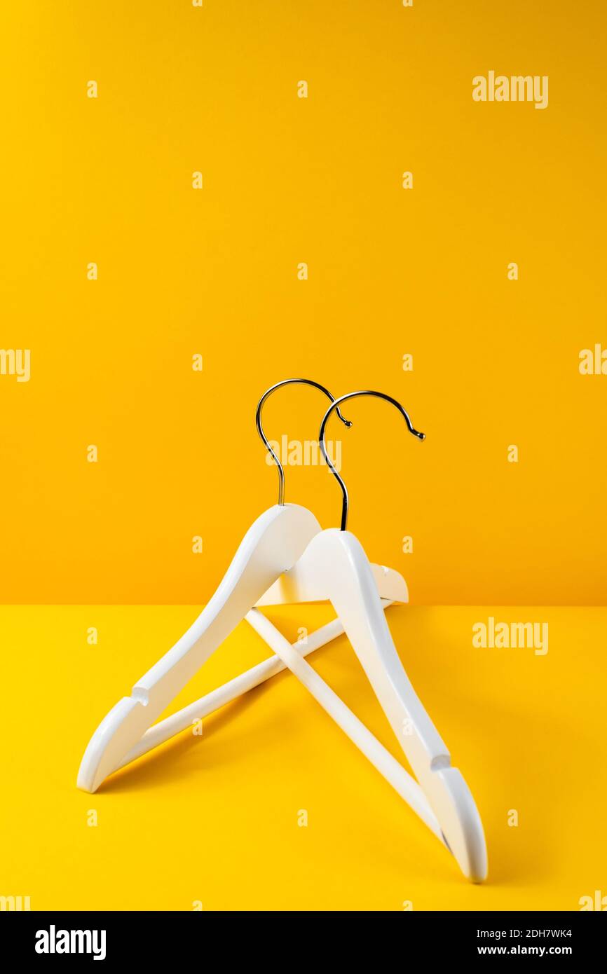 Vertical color image with a front view of a white hangers on a yellow background. Sales clothes concept. Stock Photo