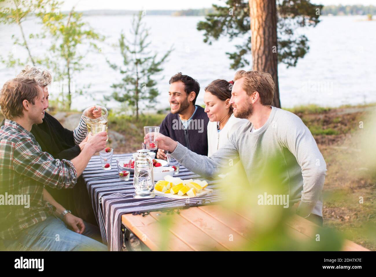 Friends enjoying while having lunch at lakeshore Stock Photo