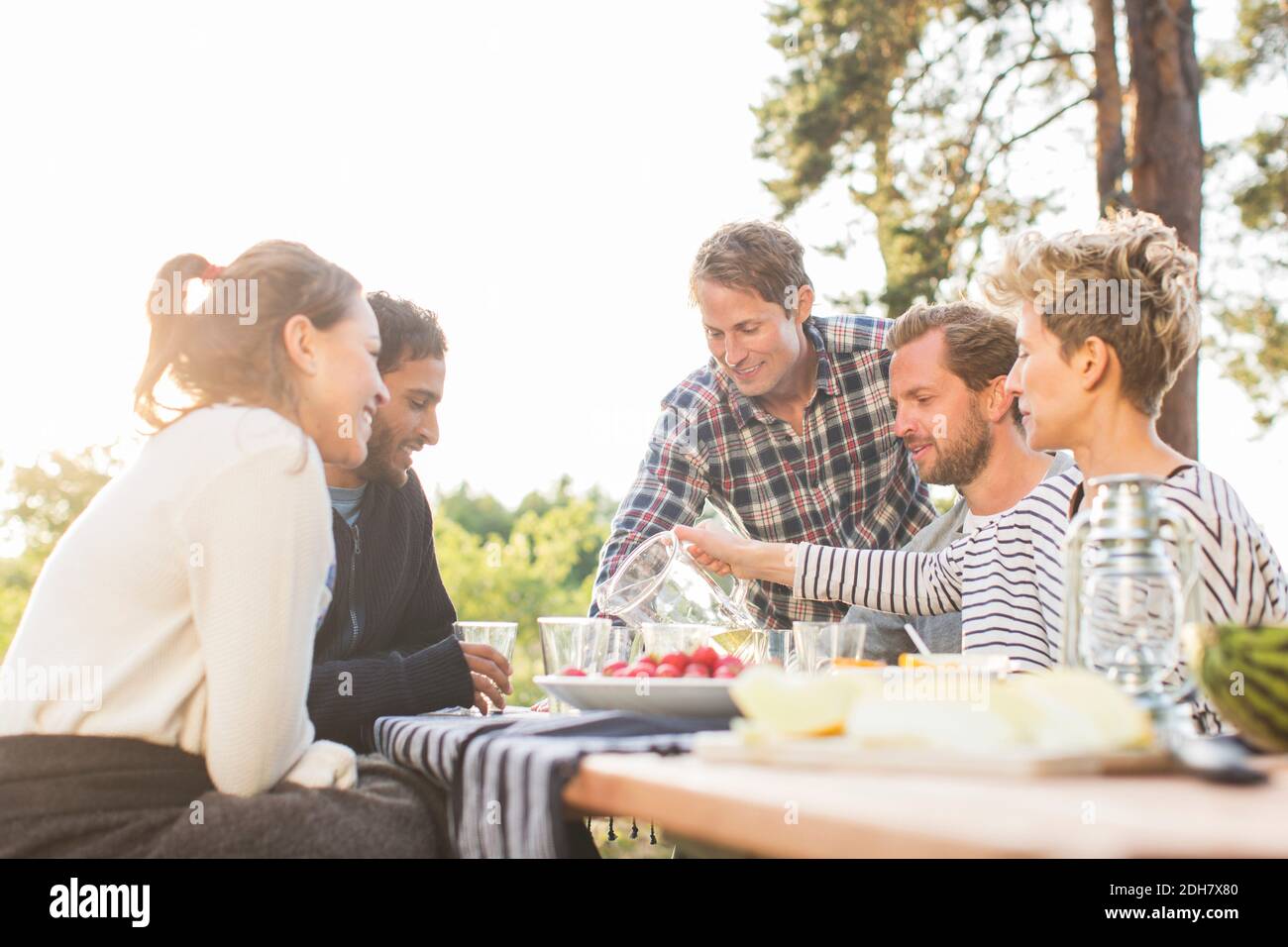 Friends having lunch at picnic table against clear sky Stock Photo